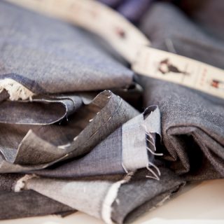 Close de tecidos jeans de cor cinza escura dobrados com as pontas amassadas.